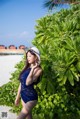 A woman in a blue swimsuit and a white hat on the beach.