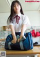 A woman in a school uniform holding a duffel bag.